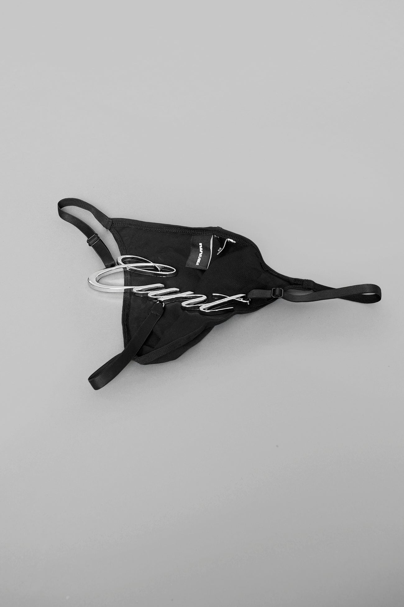 Model wearing black metal logo thong with adjustable straps
