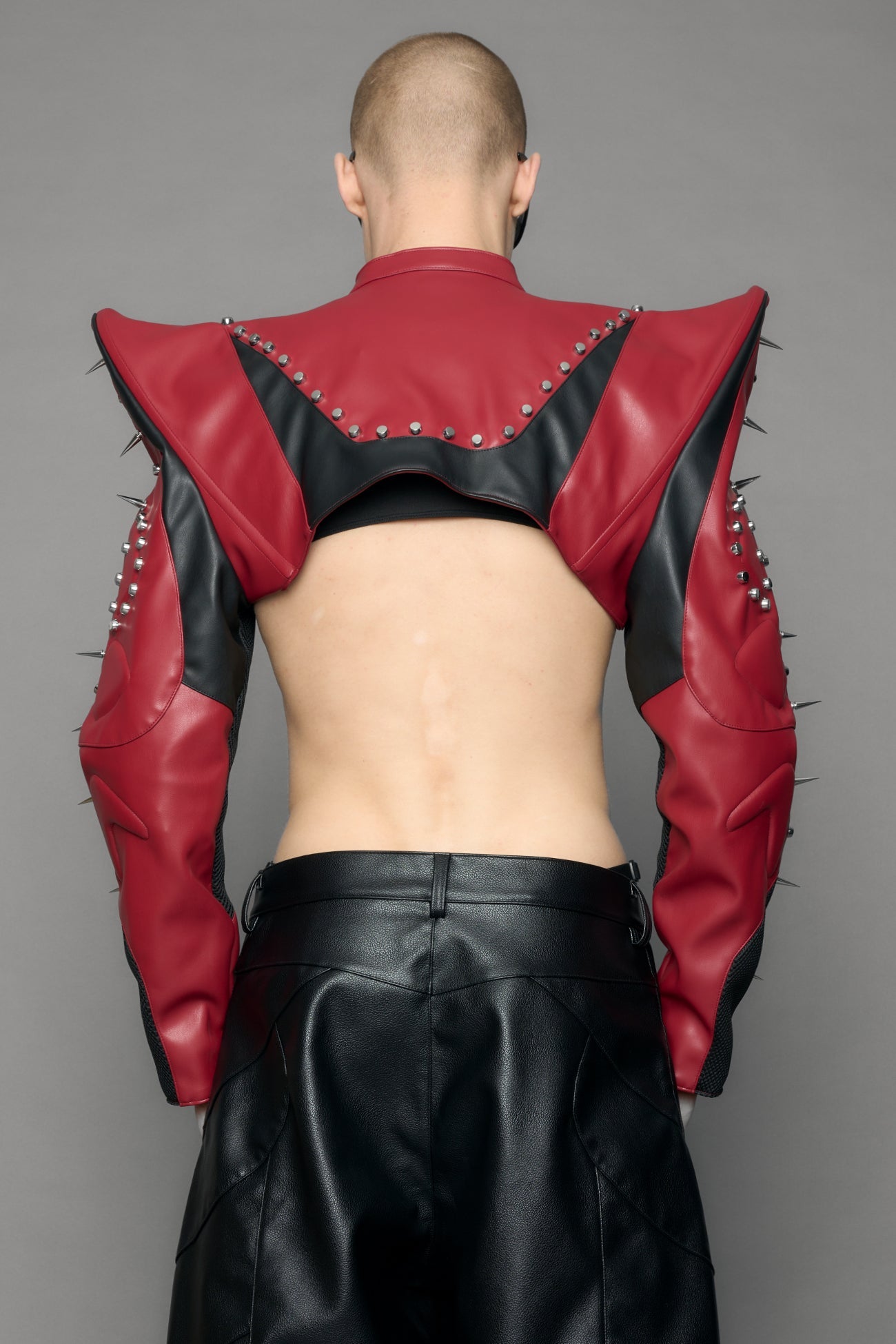 Model wearing a red studded leather choker jacket with cut-out design