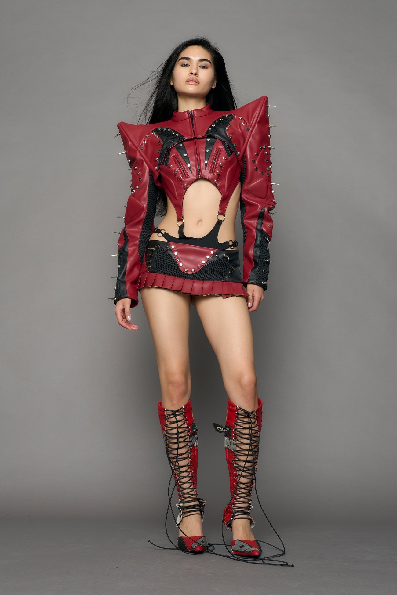 Model wearing a red studded leather choker jacket with cut-out design
