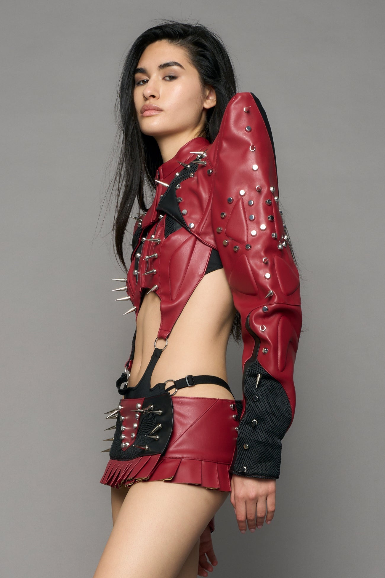 Model wearing a red studded leather choker jacket with cut-out design