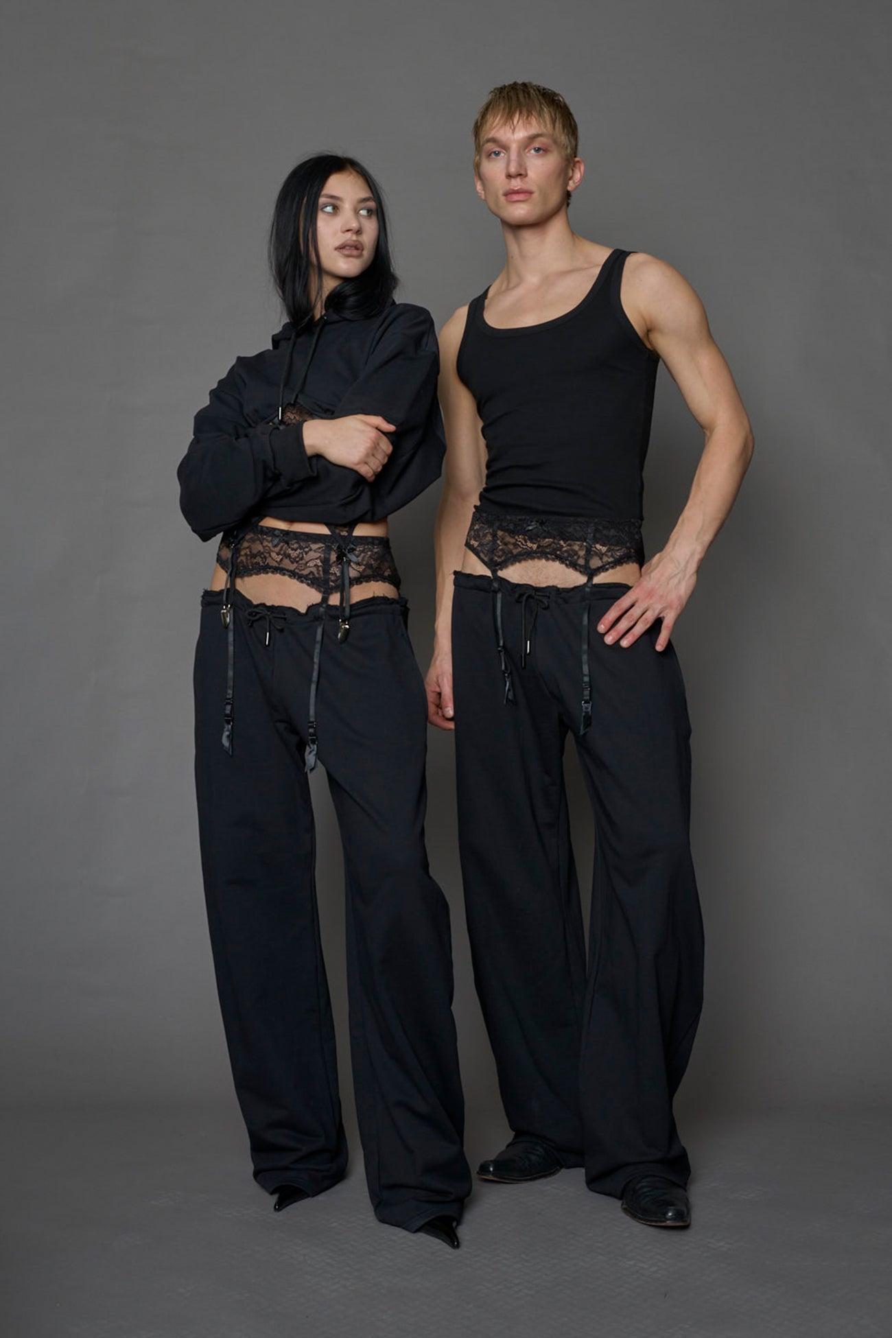 male and female model wearing a black low waist jogger with a lace suspender belt