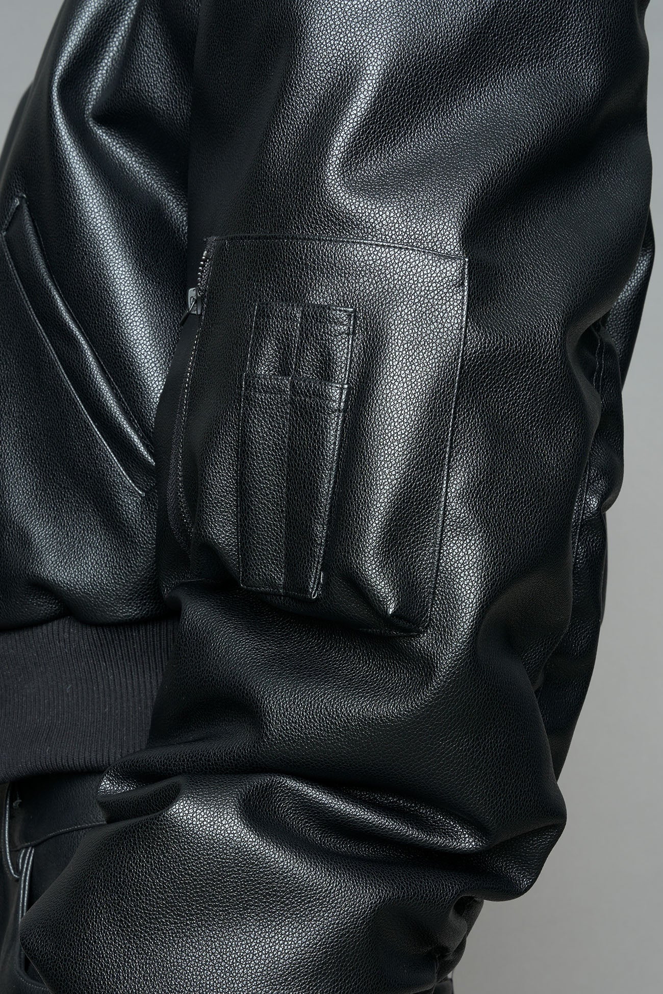 model wearing black vegan leather bomber jacket with large shoulders