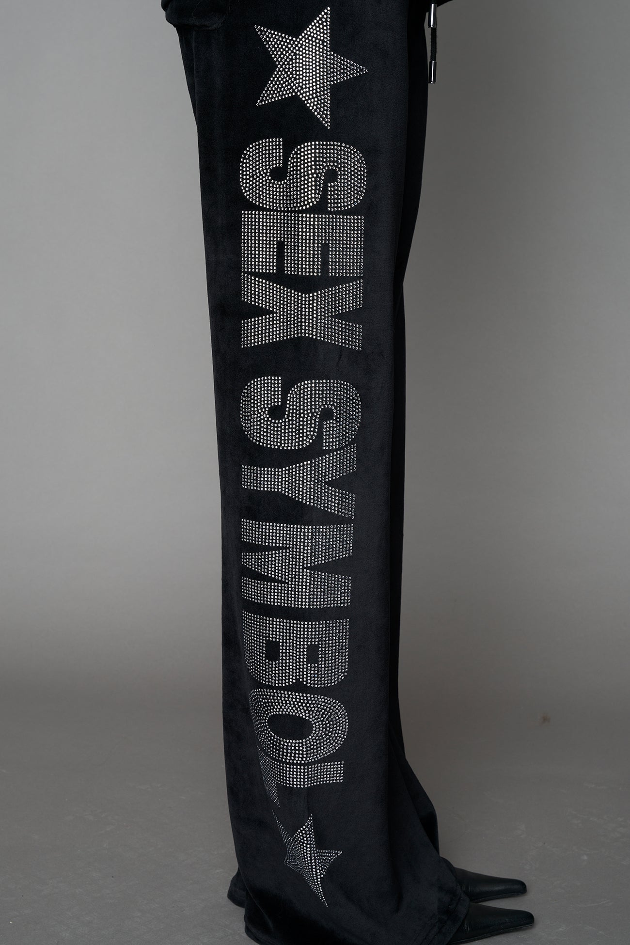 Black velour pants with NAMILIA x Symbol rhinestone detailing and a fitted straight-leg silhouette