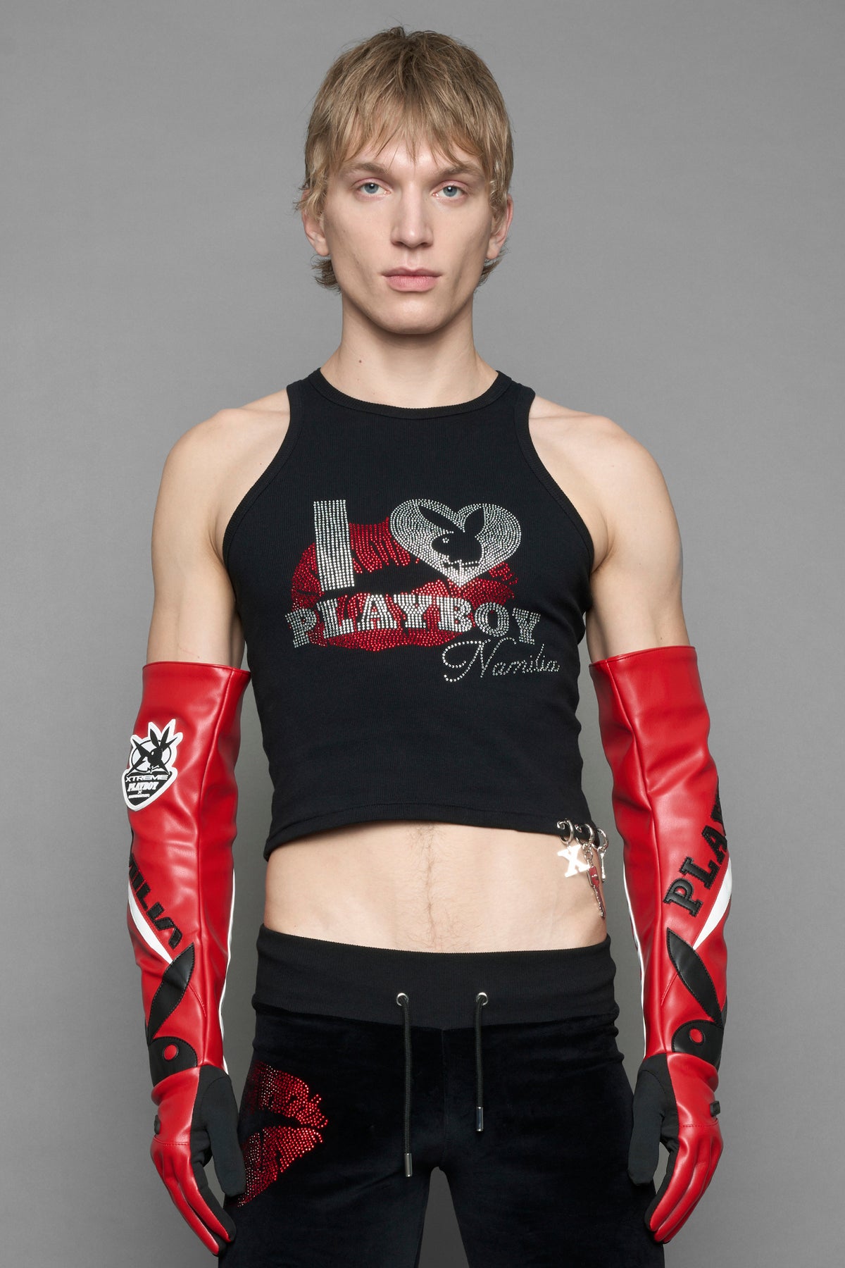 A model wears long motocross inspired red vegan Leather gloves with white and grey style paneling and black PU Leather 'Namilia' and 'Playboy' embroidery and a 'Playboy x Namilia' Rubbertag.
