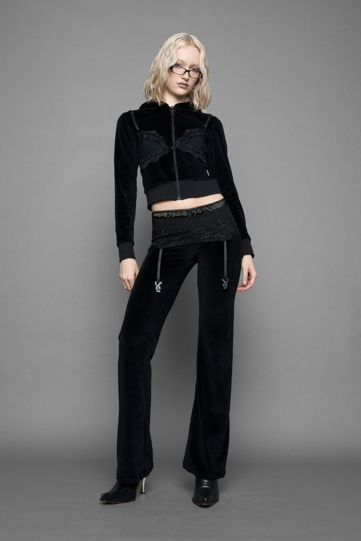 model is wearing a black velvet cropped zip-up hoodie with a black lace bralette and a Playboy branded key formed Zipper Pull