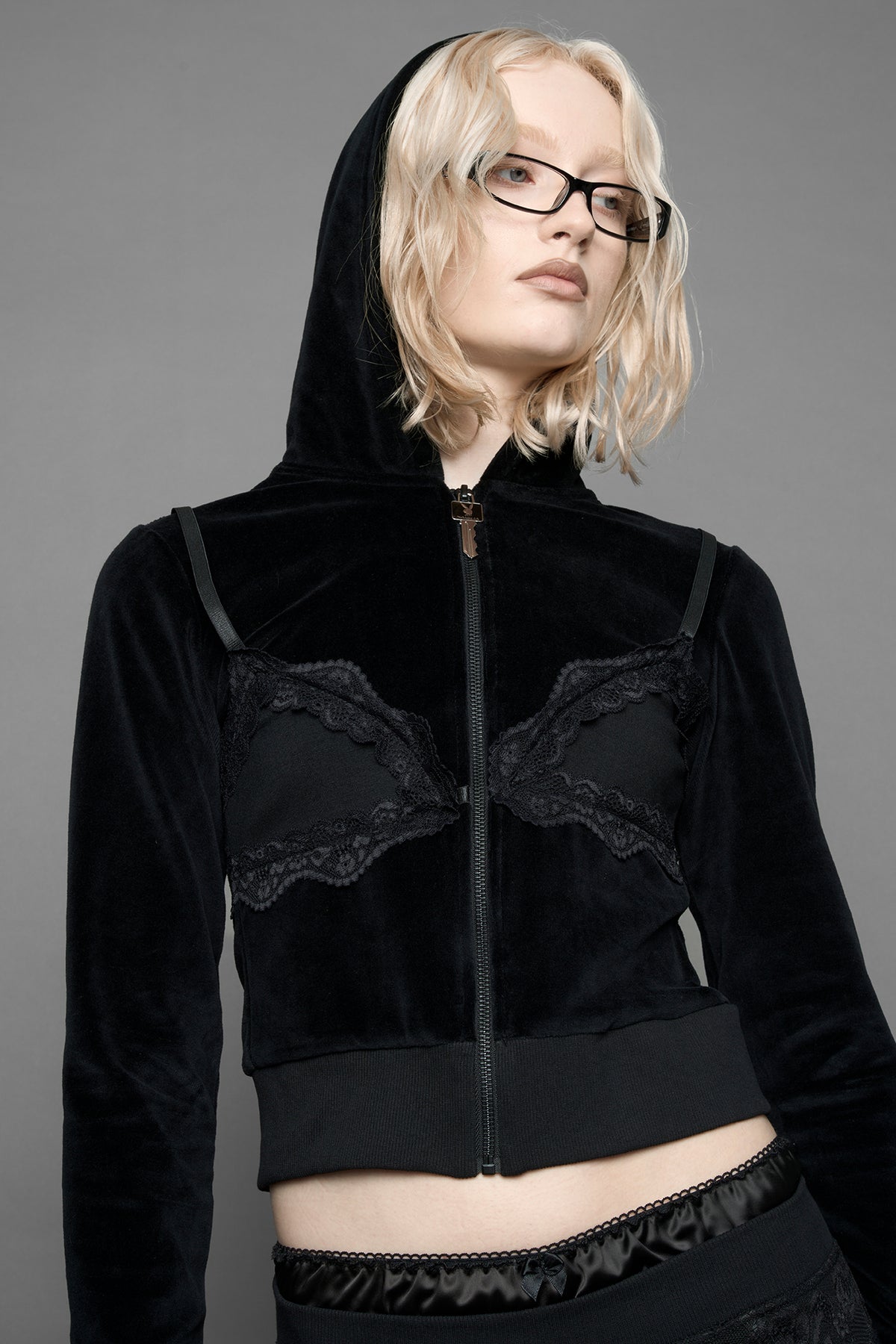 model is wearing a black velvet cropped zip-up hoodie with a black lace bralette and a Playboy branded key formed Zipper Pull
