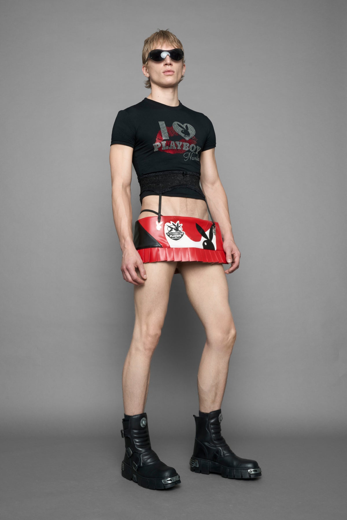 model wearing a red vegan leather wrap mini skirt with a black PU leather Bunny embroidery and a branded 'Playboy X Namilia' Rubbertag.