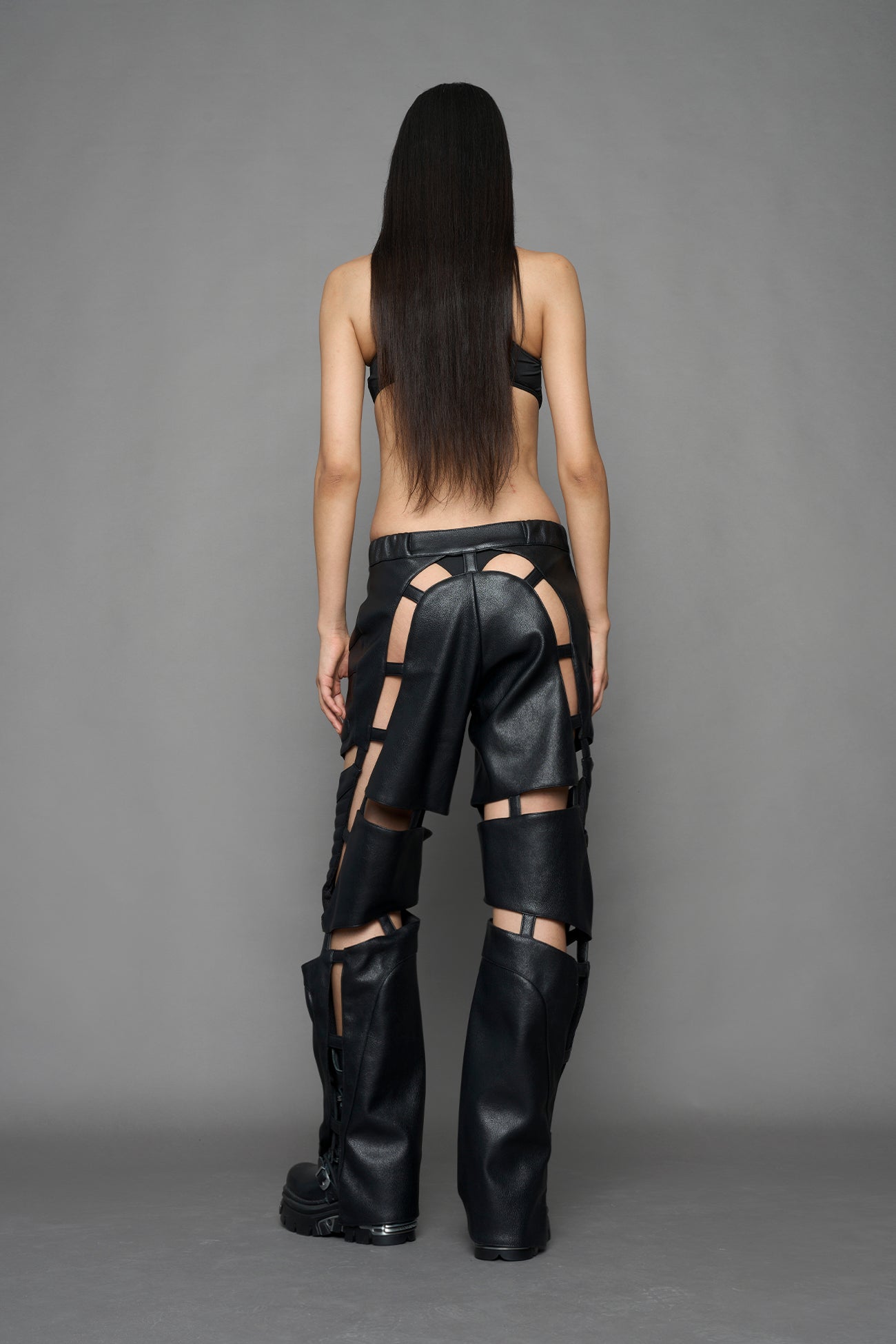 model wearing black vegan leather pants with cu outs