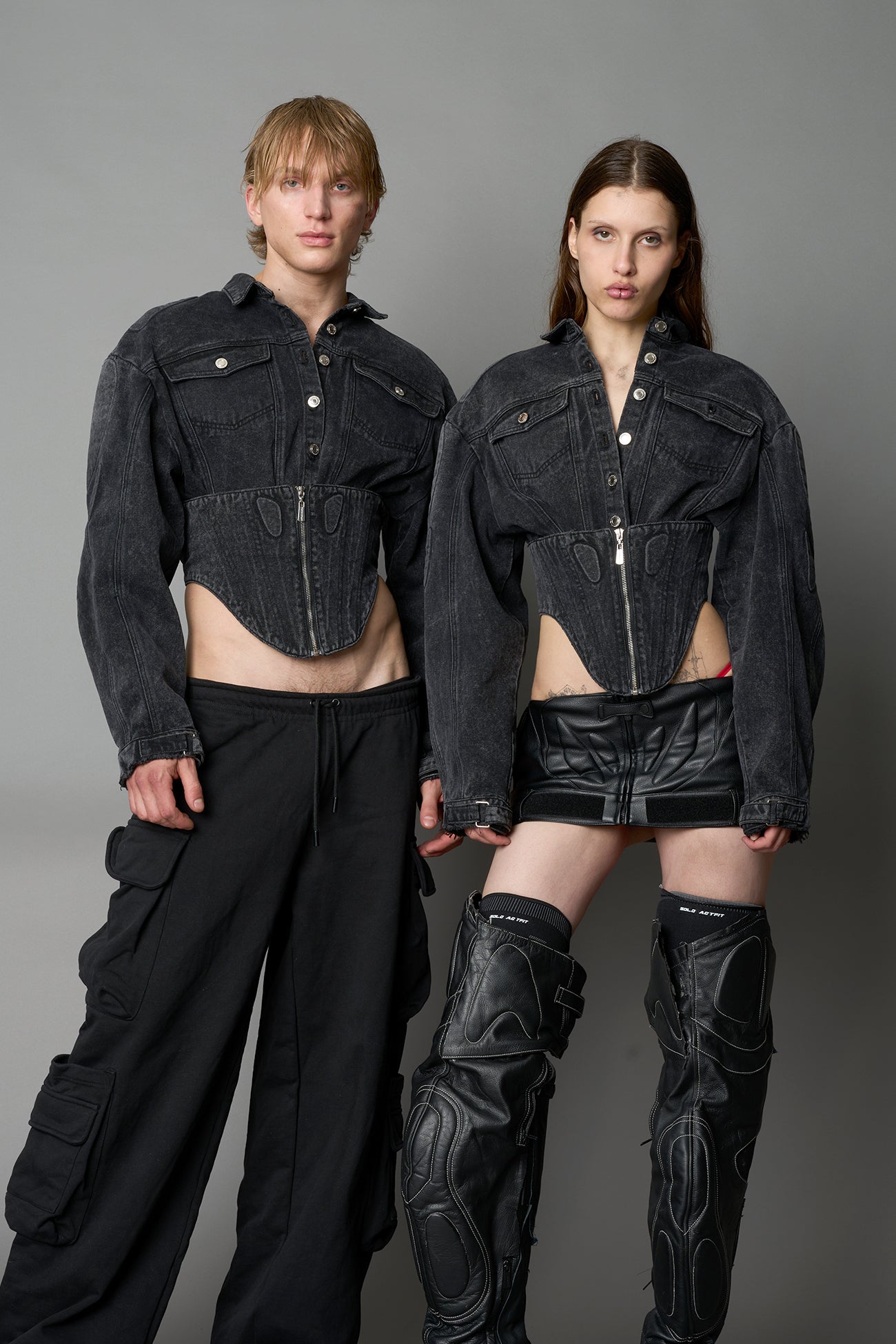 Front view of black washed denim jacket with structured corset waist and moto-style silhouette

