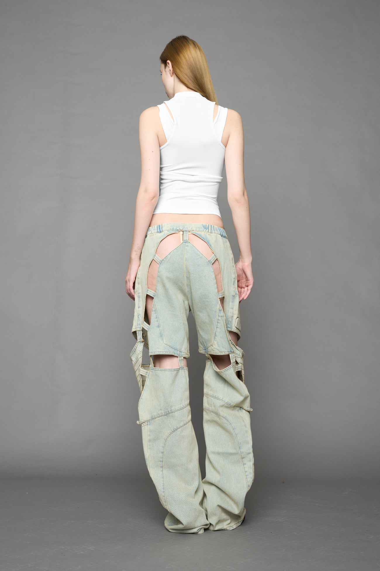 model wearing blue light wash denim pants with motocross inspired cut outs