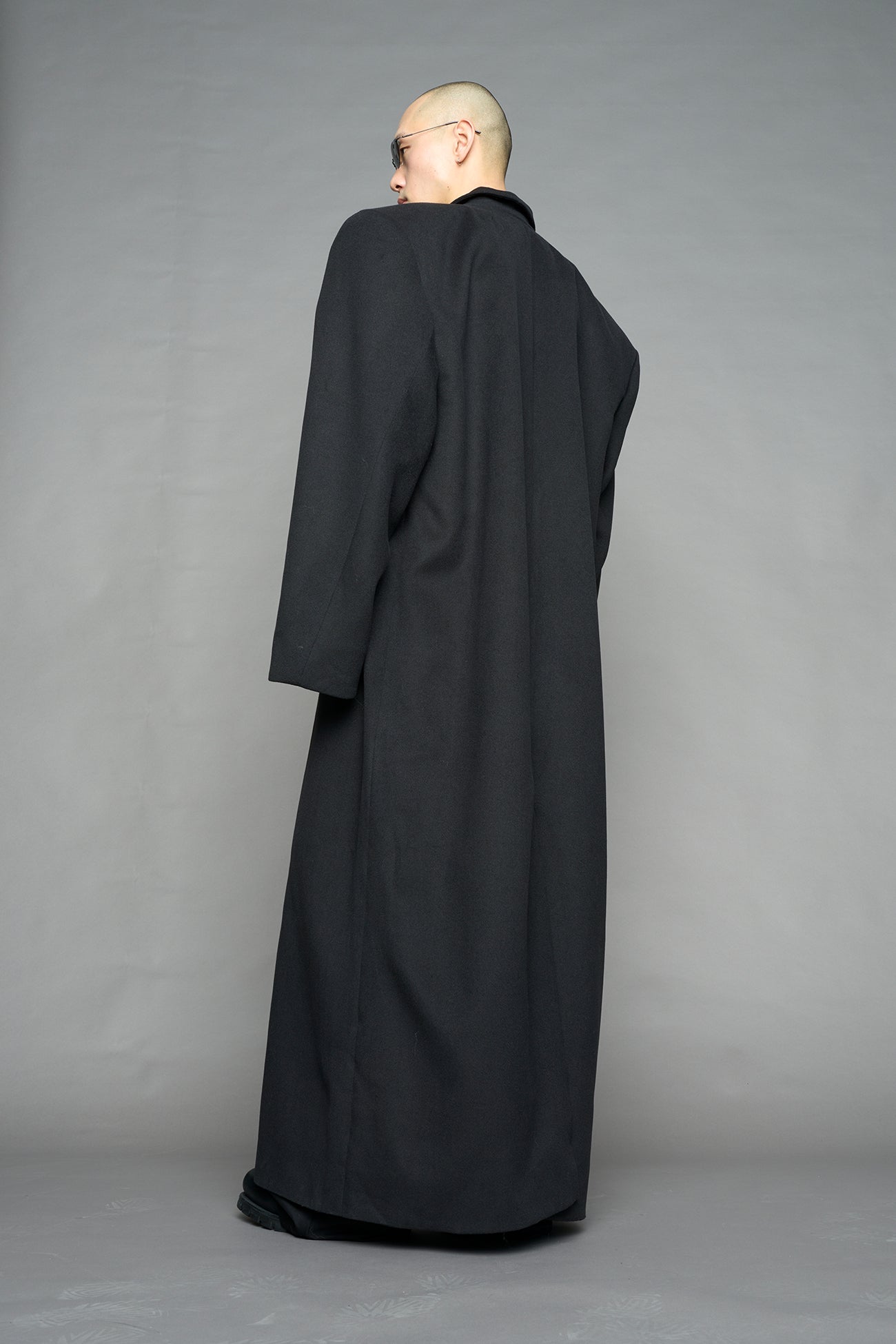 Model wearing long black coat with lapel in wool blend