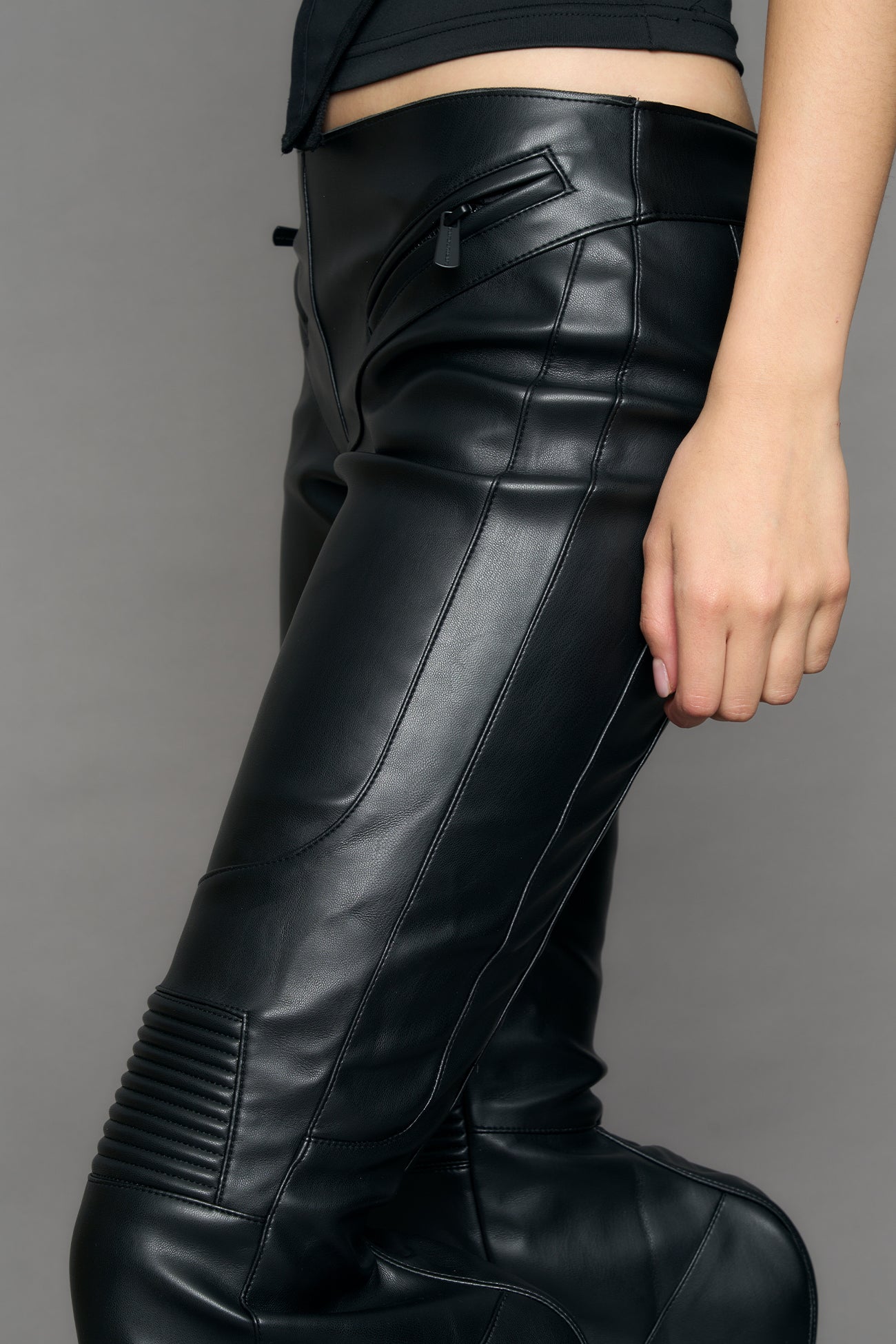 Black vegan leather stretch mutant pants with high waist, ribbed knee panels, and exaggerated flared legs by Namilia