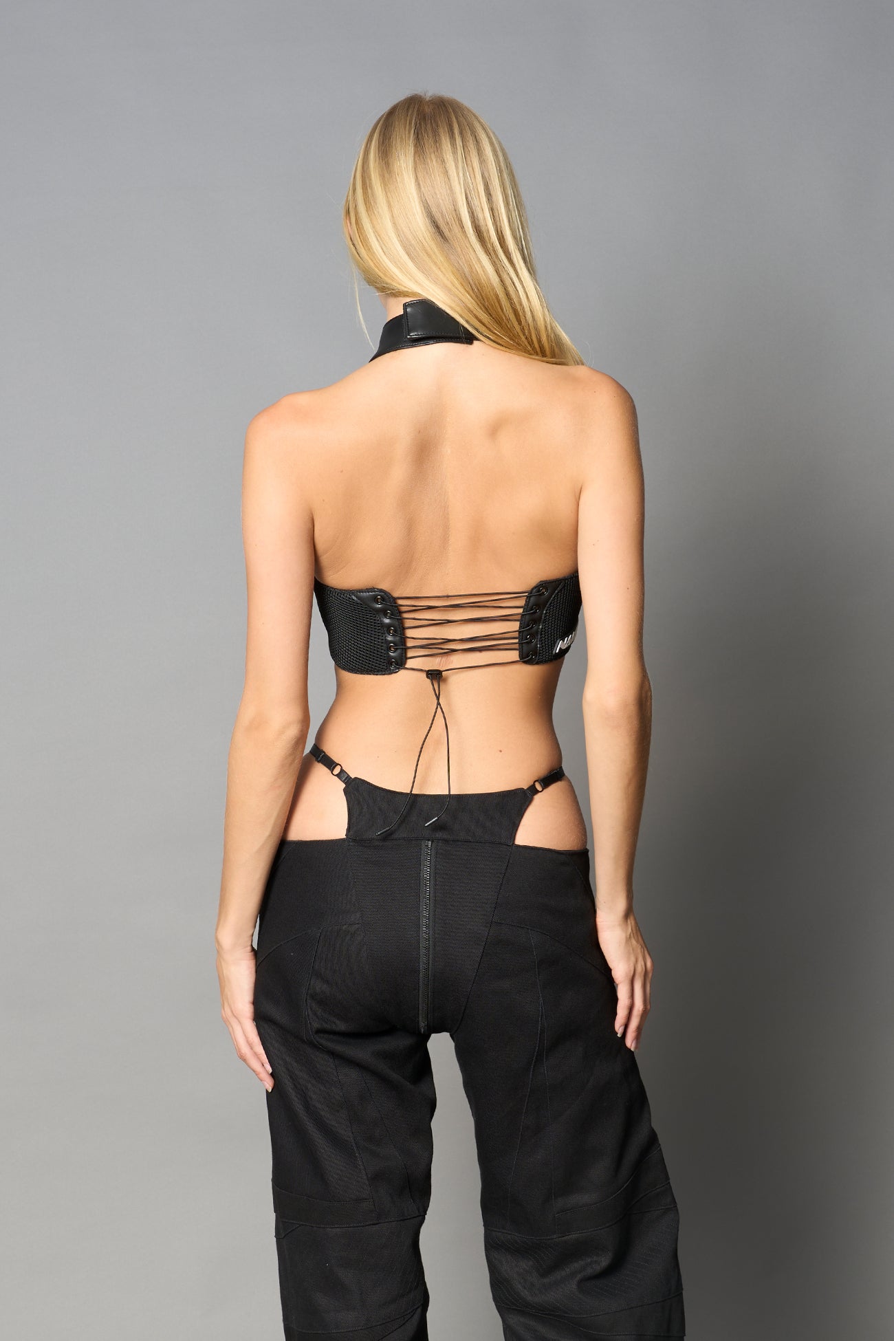 Black vegan leather neckholder crop top with lace-up front, high neck collar, and mesh panel detailing – edgy moto-inspired top for clubwear or streetwear.

v