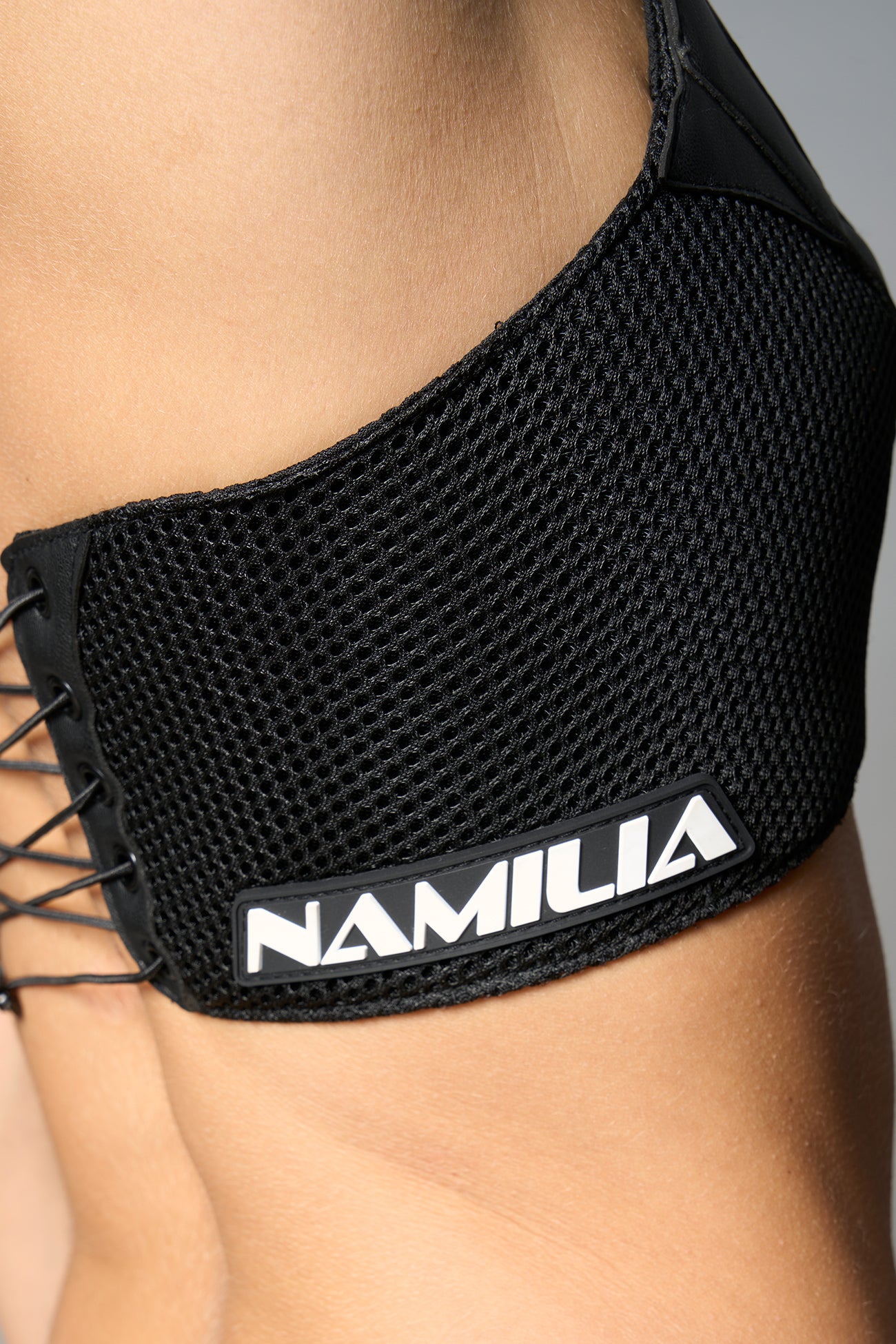 Black vegan leather neckholder crop top with lace-up front, high neck collar, and mesh panel detailing – edgy moto-inspired top for clubwear or streetwear.

