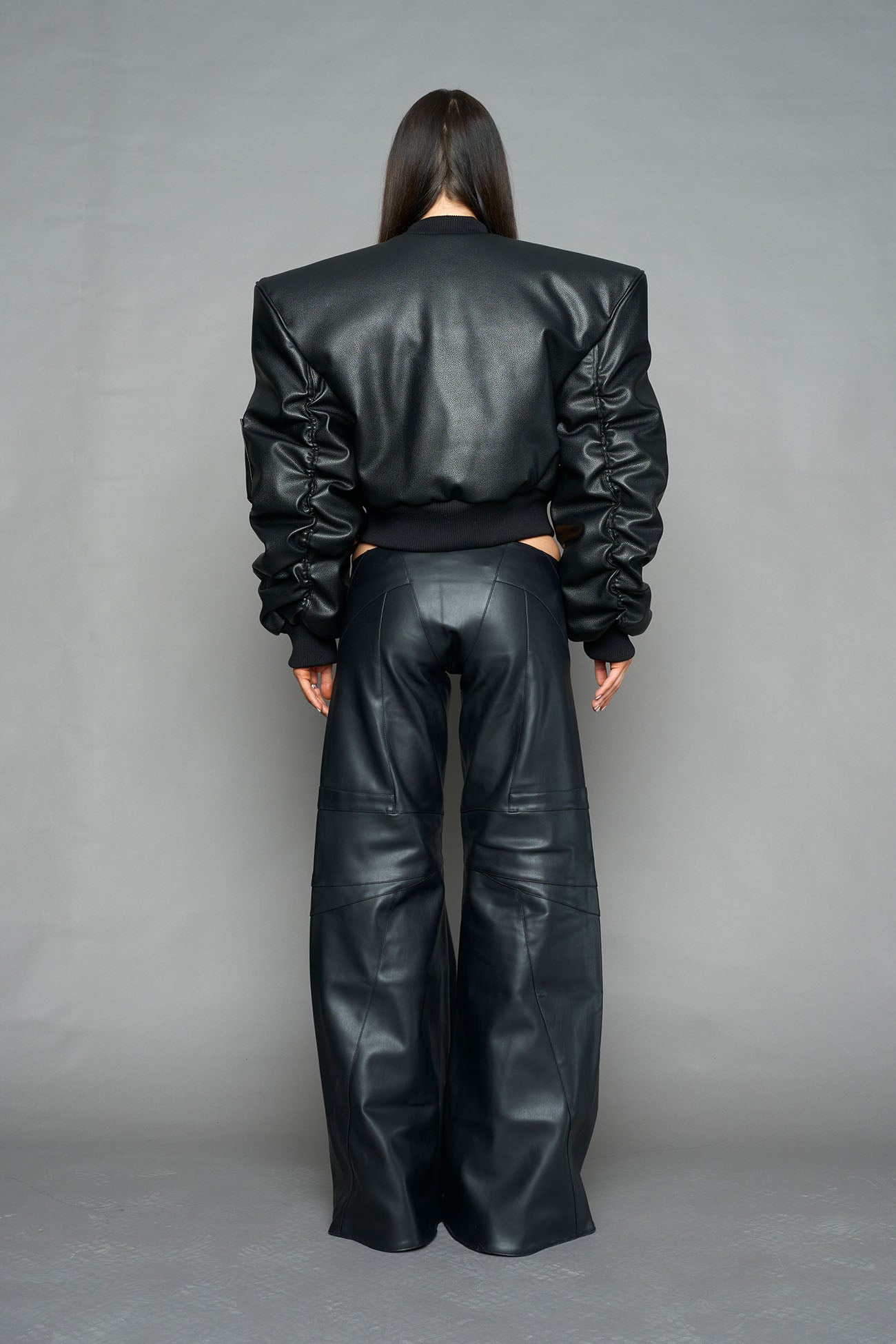 model wearing black vegan leather bomber jacket with large shoulders