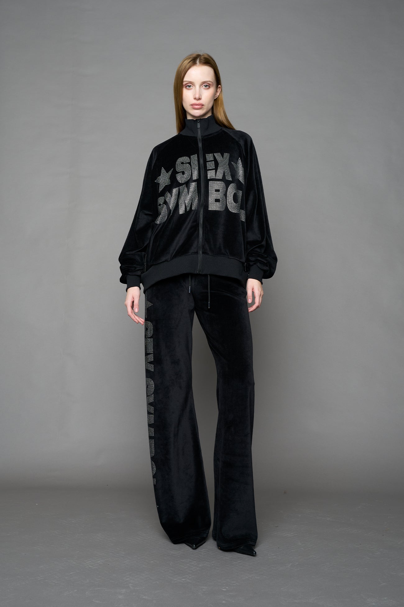 Black velour pants with NAMILIA x Symbol rhinestone detailing and a fitted straight-leg silhouette