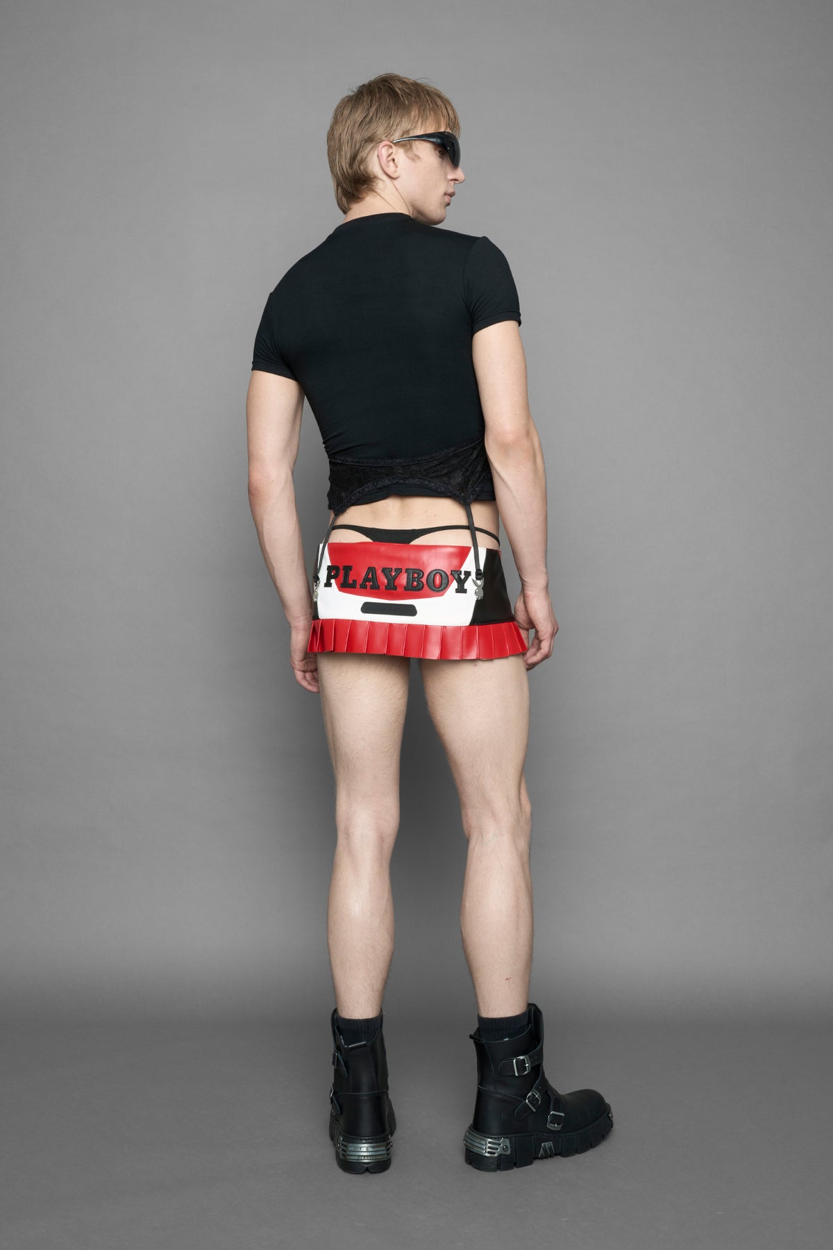 model wearing a red vegan leather wrap mini skirt with a black PU leather Bunny embroidery and a branded 'Playboy X Namilia' Rubbertag.